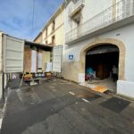 Un camion de déménagement à l'arrêt portes arrières ouvertes devant un bâtiment