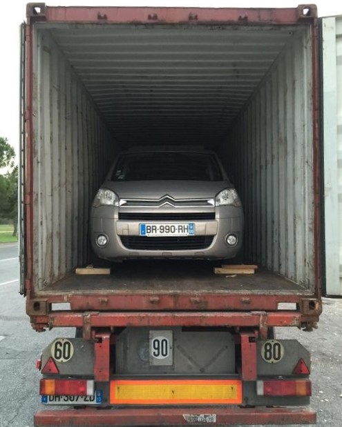 Une voiture dans un container transportée par camion